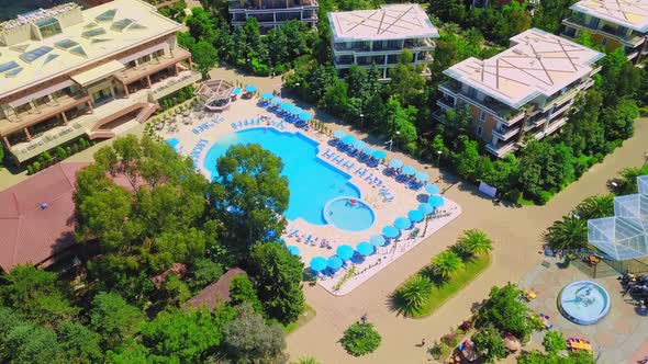 Vacationers swim and sunbathe by the hotel pool on a sunny day,view from a drone