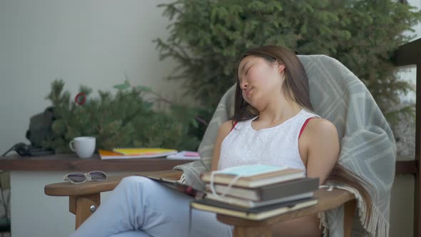 Exhausted Overworked Young Asian Woman Sleeping in Armchair on Deck