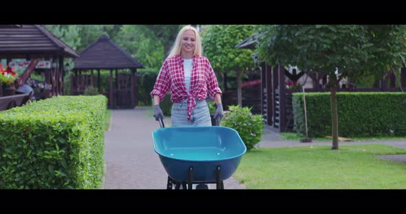 Caucasian Woman Walking at Garden with Blue Wheelbarrow