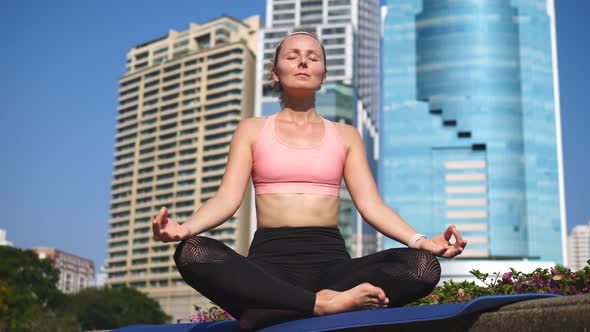 Young Healthy Woman Meditating And Doing Yoga In City Outdoors