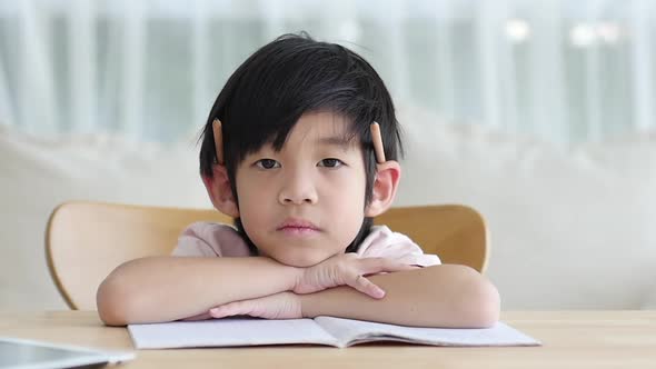 Unhappy Asian Child Working On Hard Homework At Home Alone