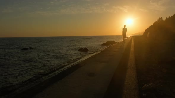 Man Walks Along the Seashore at Sunset, the Concept of Travel and Relaxation.