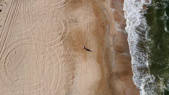 Woman in a White Shirt Runs Along a Sandy Beach