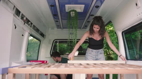 Man and Woman preparing new build van camper, with shelve and decoration indoors,close up