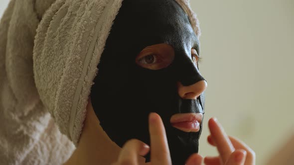 Close Up Footage of a Woman Apply Paper Black Mask Skin Care