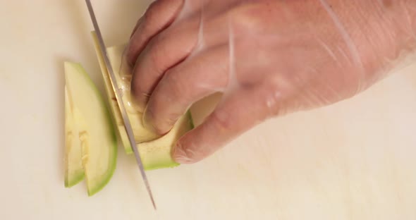 Sushi Chef Slicing Avocado On A White Chopping Board For Sushi Dish In The Kitchen. - high angle sho
