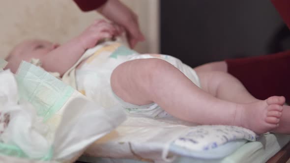 Mom changes a diaper to a newborn baby.