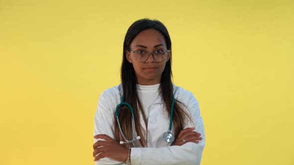 Close-up of Mixed-race Female Doctor Spreading Hands To the Sides on Yellow Background.