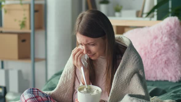 Heartbroken Young Woman Sitting on Sofa Crying Eating Ice Cream