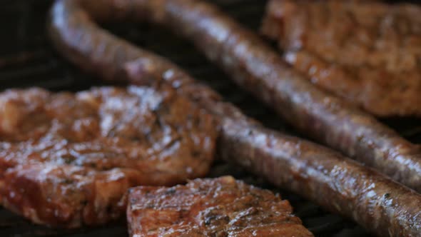 Sizzling sausage and pork on a barbecue CLOSE UP and SLIDE