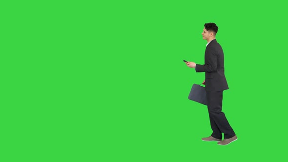 Happy Successful Businessman Dancing Listening Music From the Phone And Walking on a Green Screen