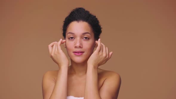 Beauty Portrait of Young African American Woman Striking Face with Fingers and Giving Gentle Skin