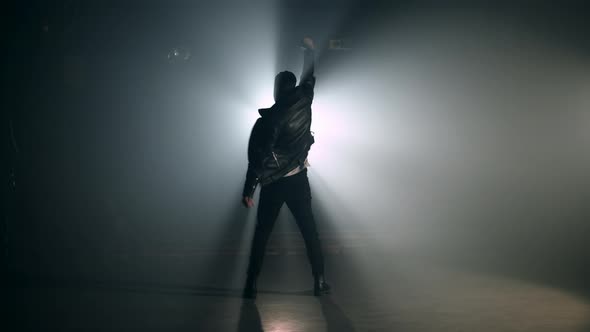 Man Stands Back on Smoky Stage. View of Guy Raises Hand Up As Gesture of Success