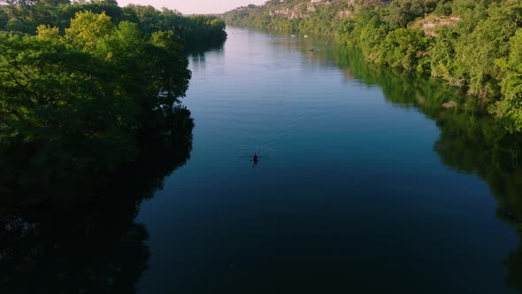 Kayaker paddling through glassy water during sunrise in Austin Texas, drone pull away to reveal down