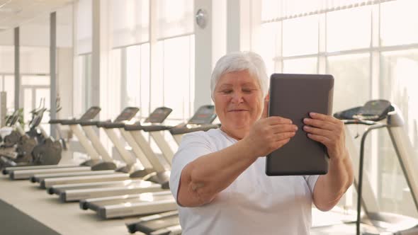 An Elderly Woman is Photographed on a Tablet Video Call Rest After Training Sends Greetings to