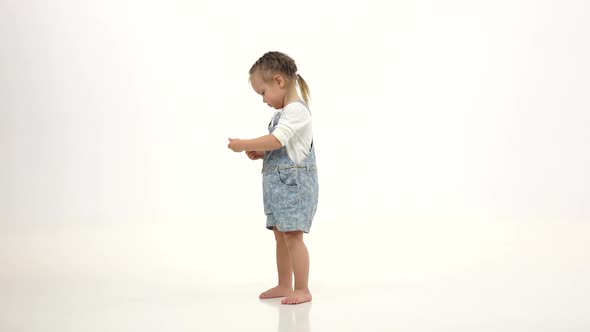 Little Girl Holds a Phone in His Hands and Talks. White Background