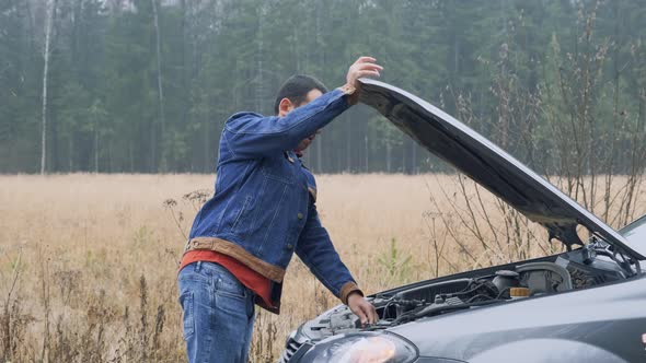 Man Opening Car Hood and Looking at Engine.