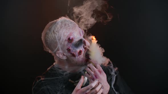Frightening Man with Halloween Zombie Bloody Makeup Spells Conjures Over Candle Voodoo Rituals