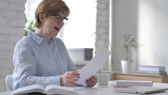 Excited Successful Old Woman Reading Documents at Workplace