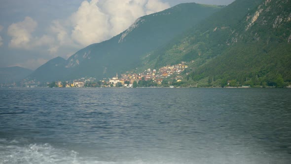 A classic luxury wooden runabout boat with the village of Predore on an Italian lake.