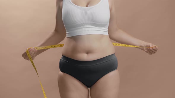 Overweight Woman in Underwear Measuring Her Fat Belly with Measure Tape