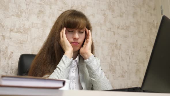 Beautiful Girl Sitting in Chair with Headache in Office for Laptop