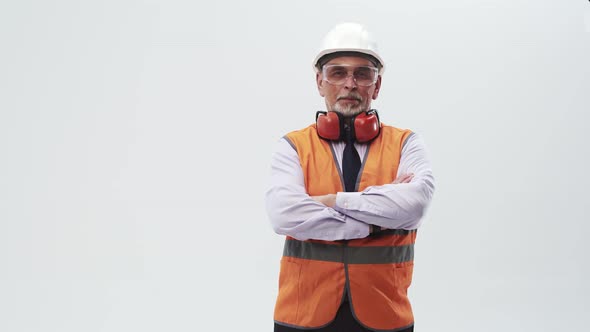 Engineer in Vest with Headphones Around Neck and Helmet Crosses Arms on Chest