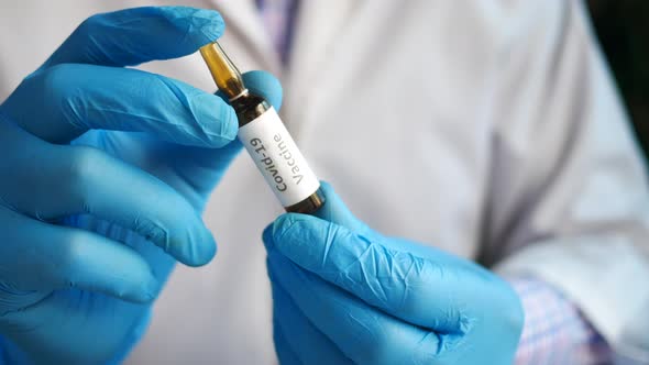 Hand in Latex Gloves Holding Glass Ampoule Vaccine with Copy Space