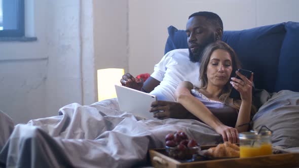 Couple Using Modern Gadgets in Bed