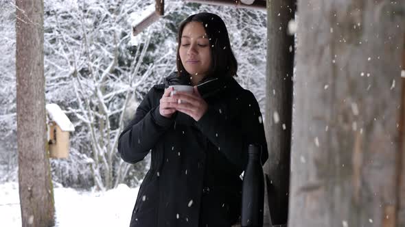 Attractive woman drink hot beverage on cold winter day during snowfall