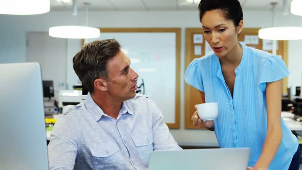 Business colleagues discussing over laptop