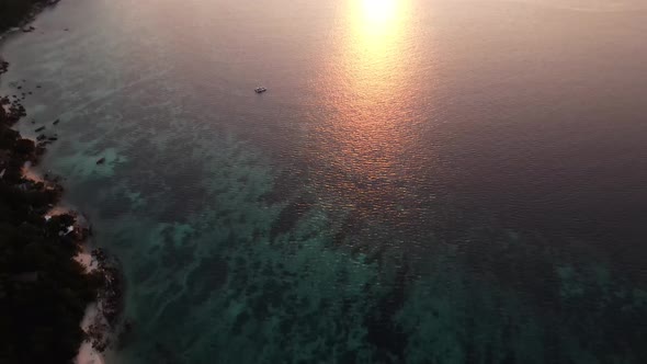 Aerial Tilt Up Over Koh Lipe To Reveal Golden Orange Sunset Over  Strait of Malacca. Establishing Sh