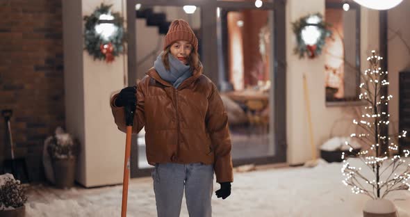 Portrait of Enthusiastic Woman with a Snow Shovel Outdoors