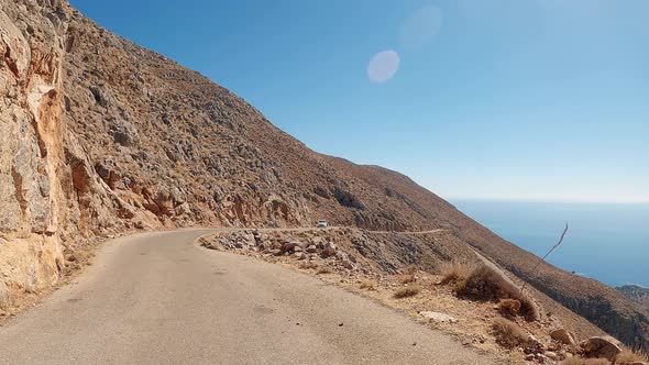 Car ride point of view on the asphalt coastal narrow road on a dramatic landscape.