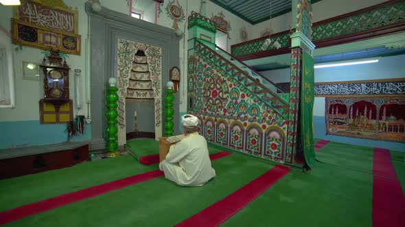 Muslim Mosque Teacher is reading the Quran in Small Historic Wooden Masjid