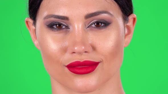 Portrait of Beautiful Woman Is Looking at the Camera and Winks. Green Screen. Close Up. Macro