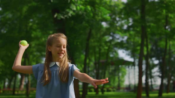 Smiling Girl Throw Ball on Green Meadow Closeup