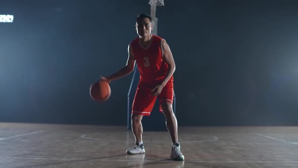 Asian Basketball Player Hits the Ball Off the Floor and Warms Up Before the Game Professional