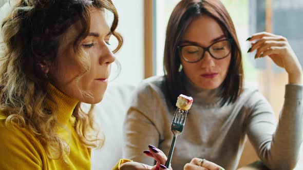 Two Young Happy Women Enjoy Delicious Syrniki with Jam Eat It with a Fork in a Beautiful Cool Place