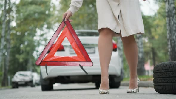 Woman Putting Warning Triangle By the Broken Car
