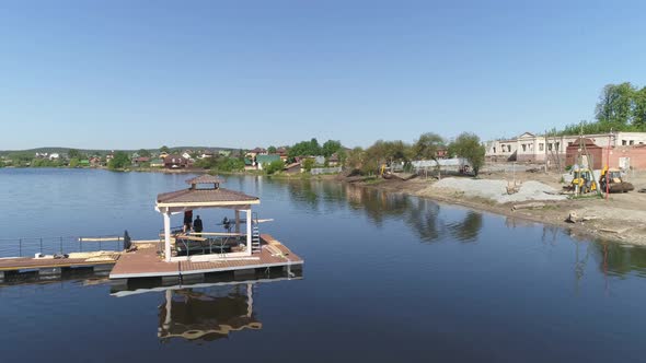 Drone view of Construction of a pier with a gazebo on the city pond. 01