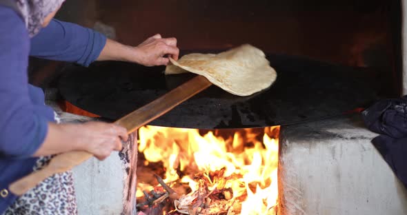 Female making bread In the oriental courtyard. Lit the firewood to bake bread