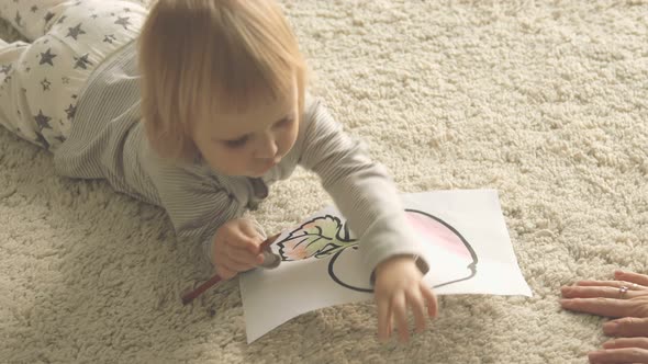 Baby girl paints picture with pencils