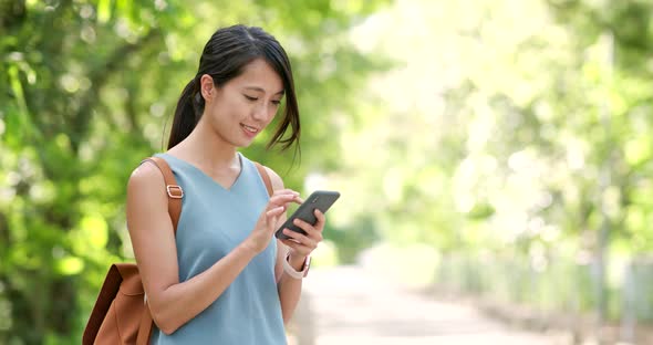 Woman use of mobile phone with the background of countryside 