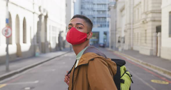 Mixed race man wearing face mask, turning around in the street
