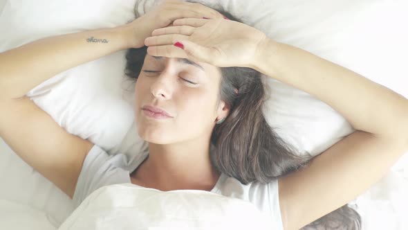 Woman lying in bed suffering from headache
