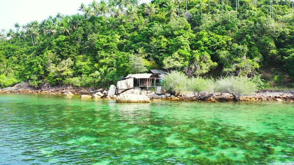 Coral reefs growing on white sand of sea bottom under calm clear water of lagoon washing rocky coast