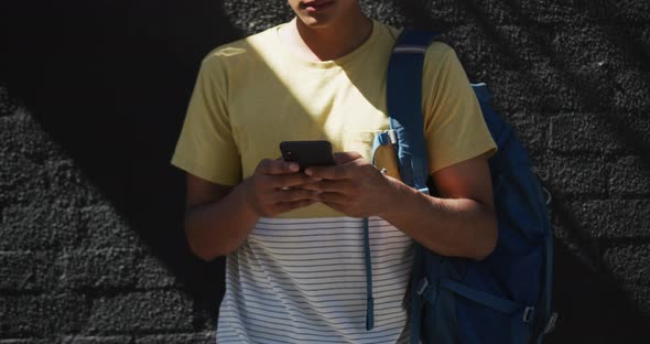Mid section of mixed race man wearing headphones and using smartphone in the street