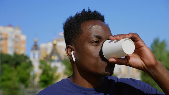 Close Up Smiling Afroamerican Man Wearing Wireless Earphones Drinks Coffee Tea