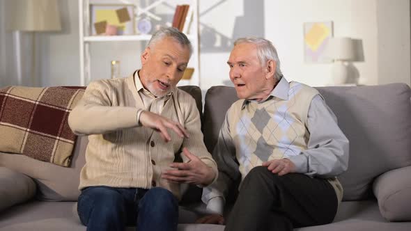 Old Man Explaining Something to Deaf Friend, Sitting on Sofa at Home, Problems